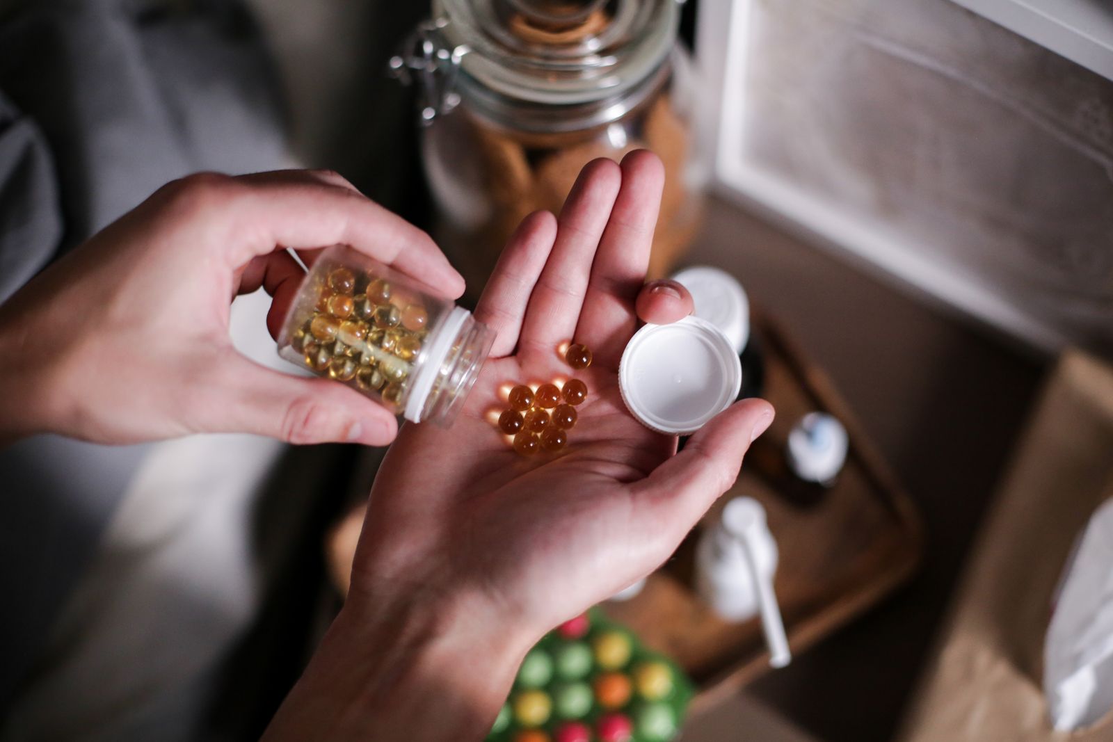Amber softgels poured from the bottle into an open palm in warm morning light — the daily dose, in real hands.