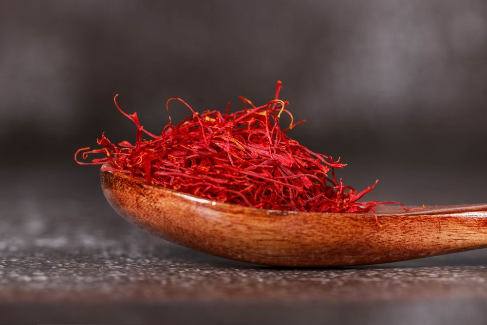 Hands sorting crimson saffron stigmas from purple crocus flowers in La Mancha at dawn. Close, tactile, the real harvest.